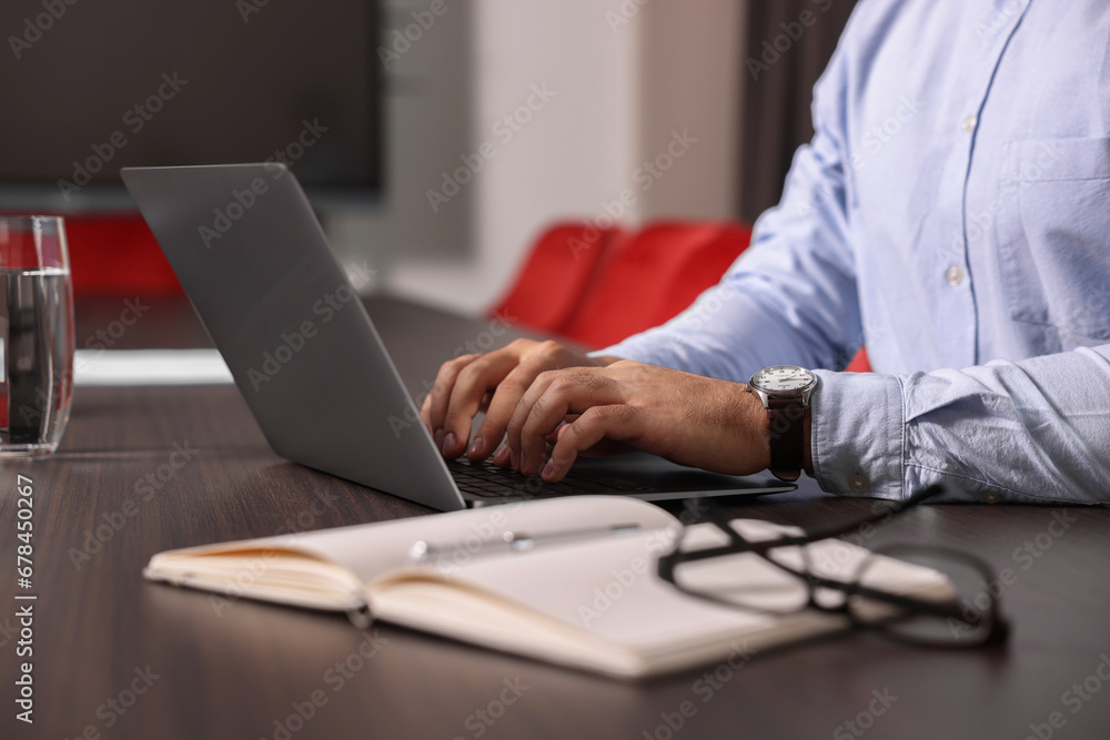 Man working on laptop at table in office, closeup Man working on laptop at table in office, closeup