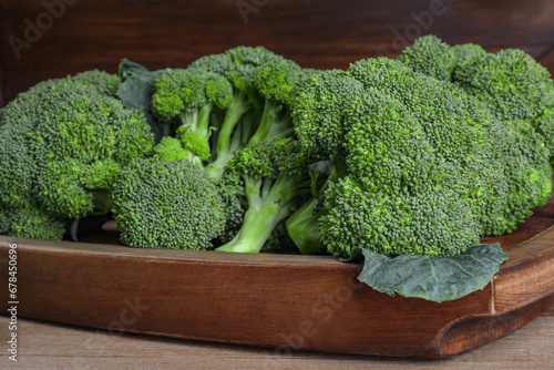 Tray with fresh raw broccoli on wooden table, closeup
