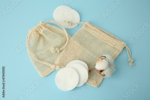 Bags, cotton pads and flower on light blue background