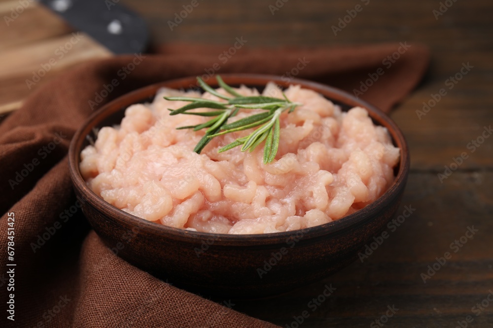 Fresh raw minced meat and rosemary in bowl on wooden table, closeup Fresh raw minced meat and rosemary in bowl on wooden table, closeup