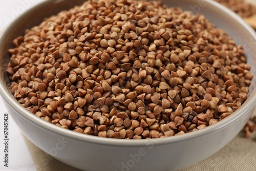 Bowl with dry buckwheat on table, closeup