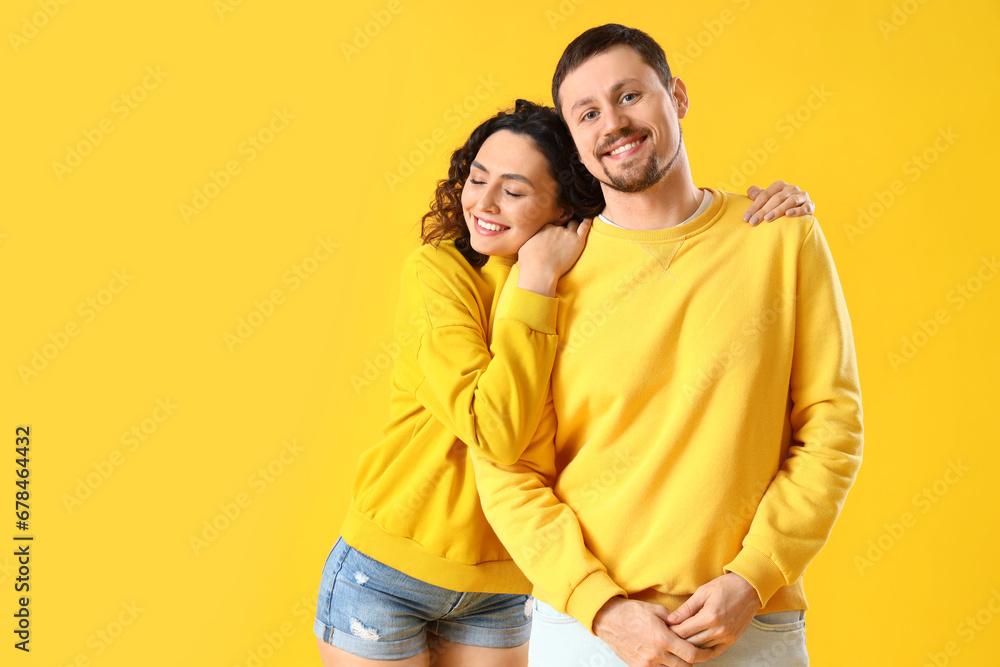 Happy young couple hugging on yellow background Happy young couple hugging on yellow background