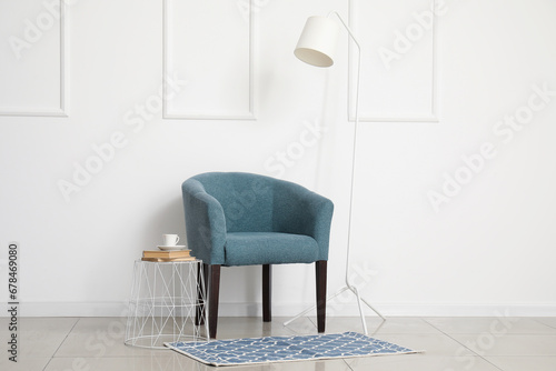 Cozy armchair and standard lamp near white wall