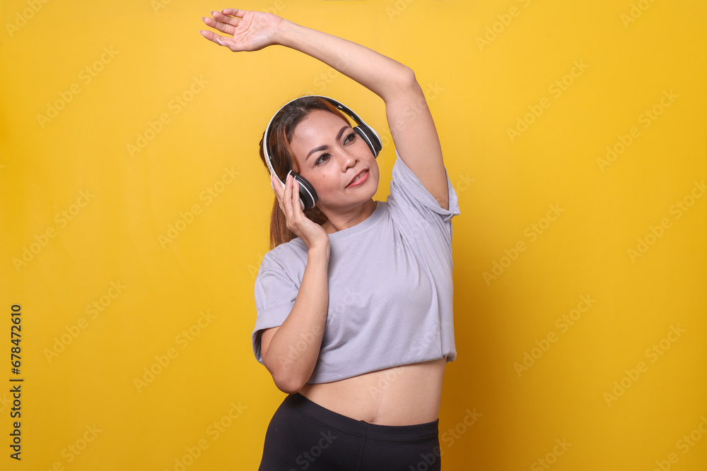 Sporty young woman dancing with headphones on yellow background Sporty young woman dancing with headphones on yellow background