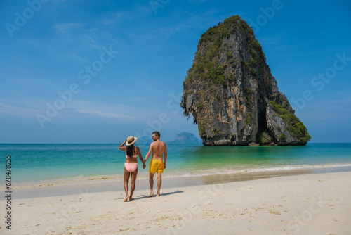 A couple of men and woman walking on the beach of Railay Beach Krabi Thailand