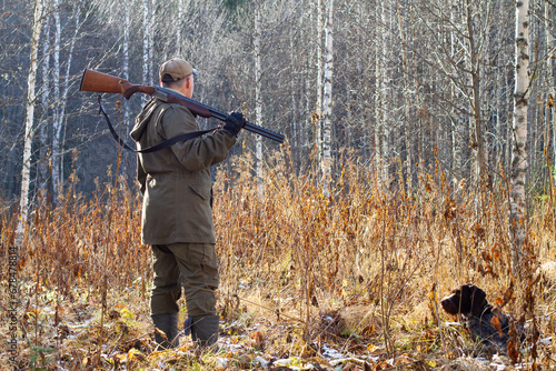 a hunter and his hunting dog in the birch forest in autumn