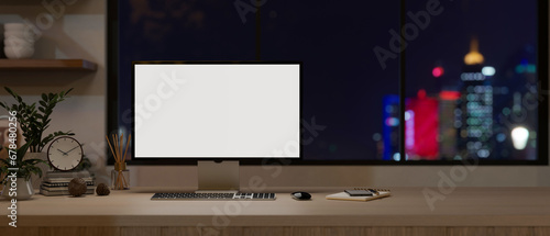 A computer monitor mockup on a wooden desk against the window with a city night light view. photo