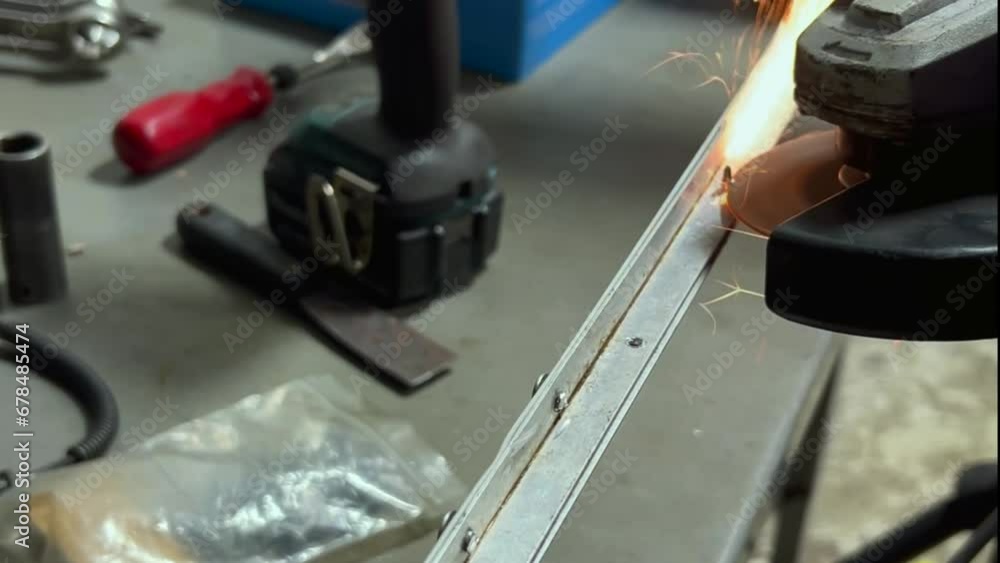 A close-up of a person using a powered metal saw to cut a screw, causing orange sparks to fly. The camera truck left, moving clockwise around the tool. A close-up of a person using a powered metal saw to cut a screw, causing orange sparks to fly. The camera truck left, moving clockwise around the tool.