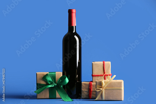 Bottle of wine and Christmas gift boxes on blue background