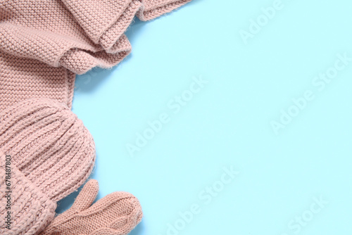 Knitted hat, scarf and mittens on color background