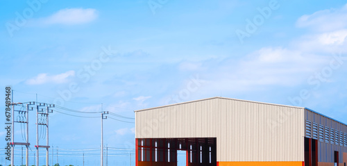 Industrial workshop building with electric poles and cable lines against blue sky background in panoramic view photo