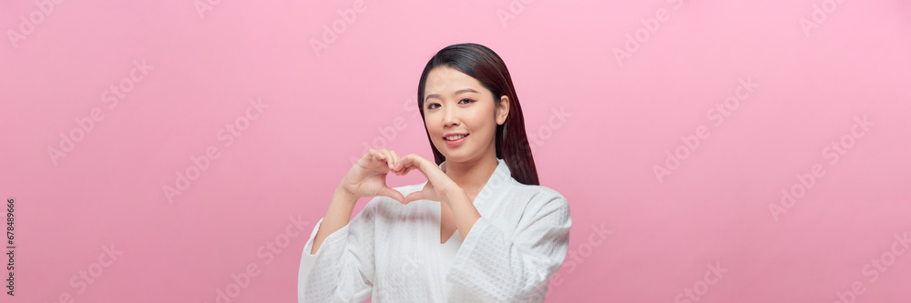 happy smiling young woman making hand heart gesture over pink background happy smiling young woman making hand heart gesture over pink background