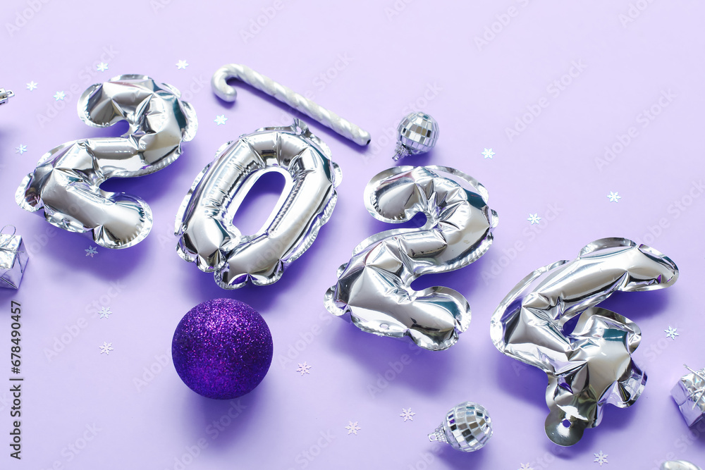 Composition with figure 2024 made of foil balloons and Christmas decorations on lilac background Composition with figure 2024 made of foil balloons and Christmas decorations on lilac background