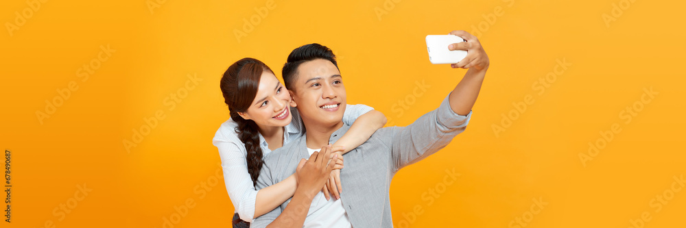 Young lovely couple taking selfie against yellow background - obrazy, fototapety, plakaty 