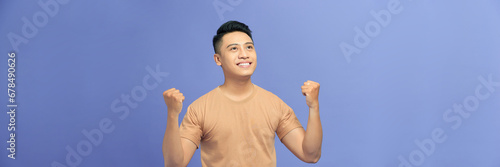 Happy ecstatic young Asian man raising his fists doing yes gesture celebrating success