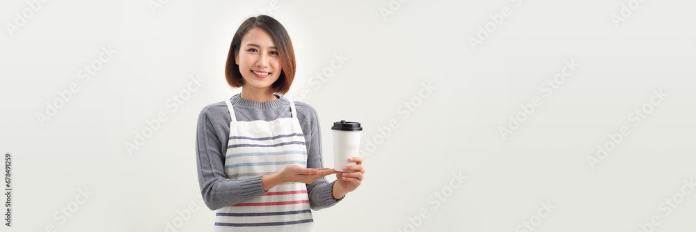 Friendly smiling asian young female in apron giving holding coffee tea hot beverage cups Friendly smiling asian young female in apron giving holding coffee tea hot beverage cups