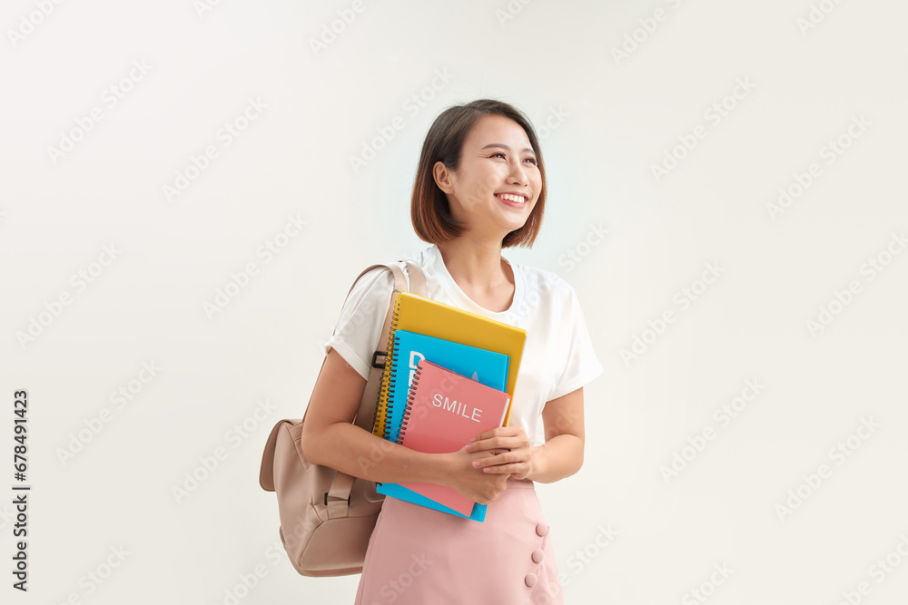 Portrait of smiling woman holding book and backpack leaning on white background Portrait of smiling woman holding book and backpack leaning on white background