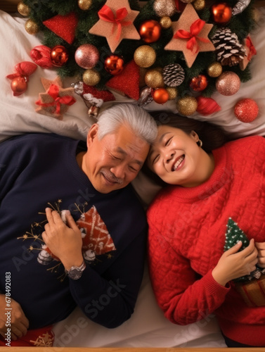 An elderly couple lay on a bed decorated with Christmas decorations