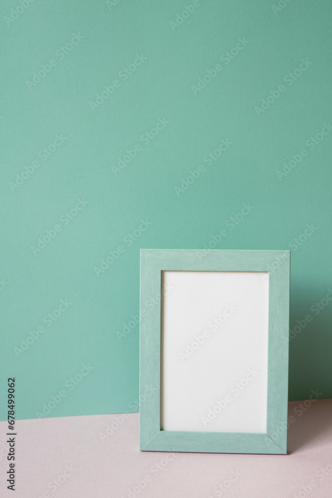 Picture frame on pink table. mint green wall background. copy space