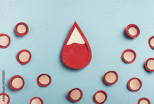 Drop of blood and red blood cells on pastel blue background. Iron deficiency anemia concept, low red blood cell. Top view photo