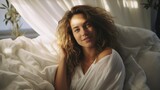 miling caucasian woman in white bed, cozy and relaxed,