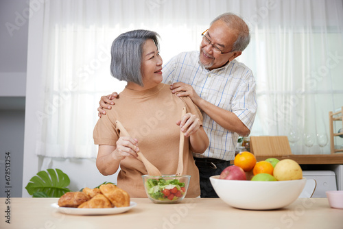 senior couple enjoy cooking salad and looking each other in the kitchen