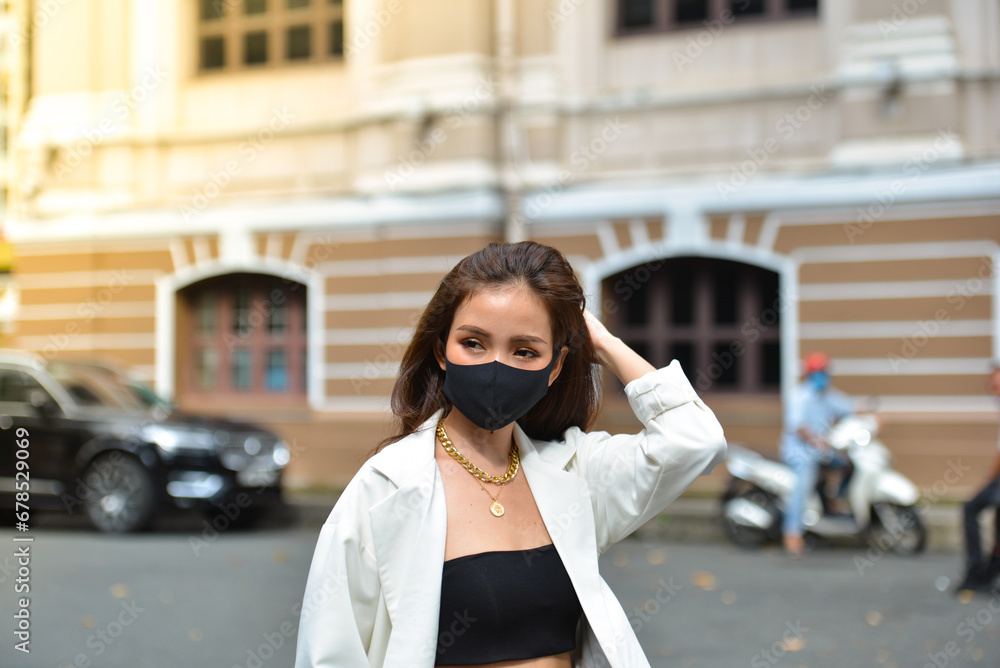 Fototapeta premium Young woman wearing sunglasses in city, colorful buildings and feel the warm. Exploring this bustling metropolis is a true adventure