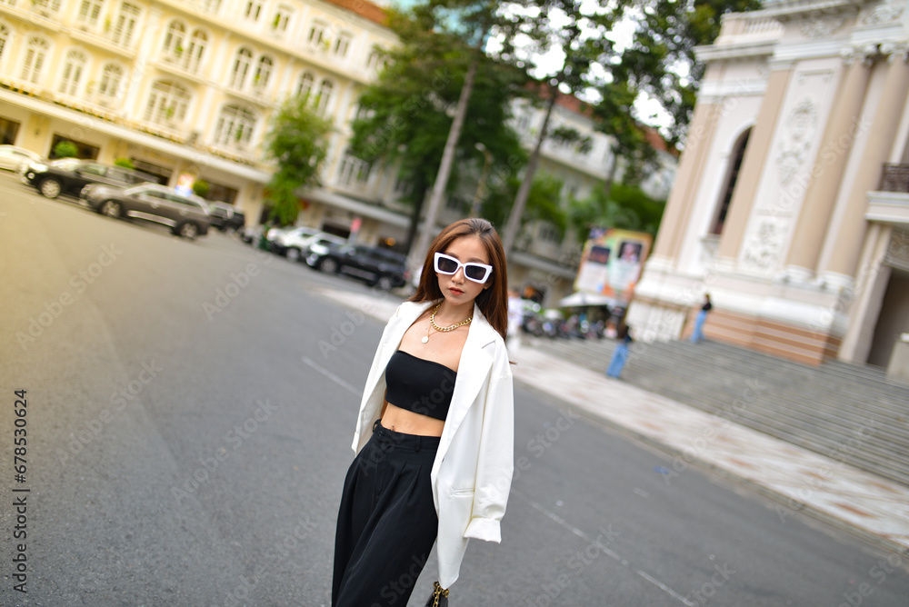 Young woman wearing sunglasses in city, colorful buildings and feel the warm. Exploring this bustling metropolis is a true adventure