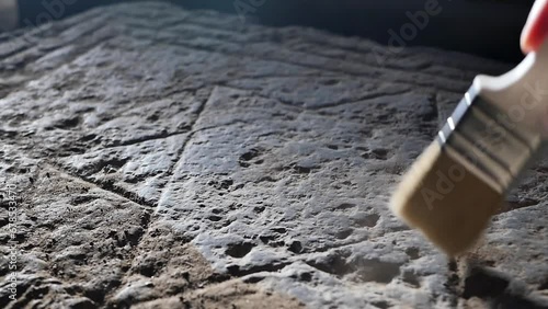 Close-up of an archaeologist and historian removing dust with a brush from an ancient stone carving of the Jewish six-pointed Star of David. The symbol of the ancient Jews is depicted on a stone slab. photo