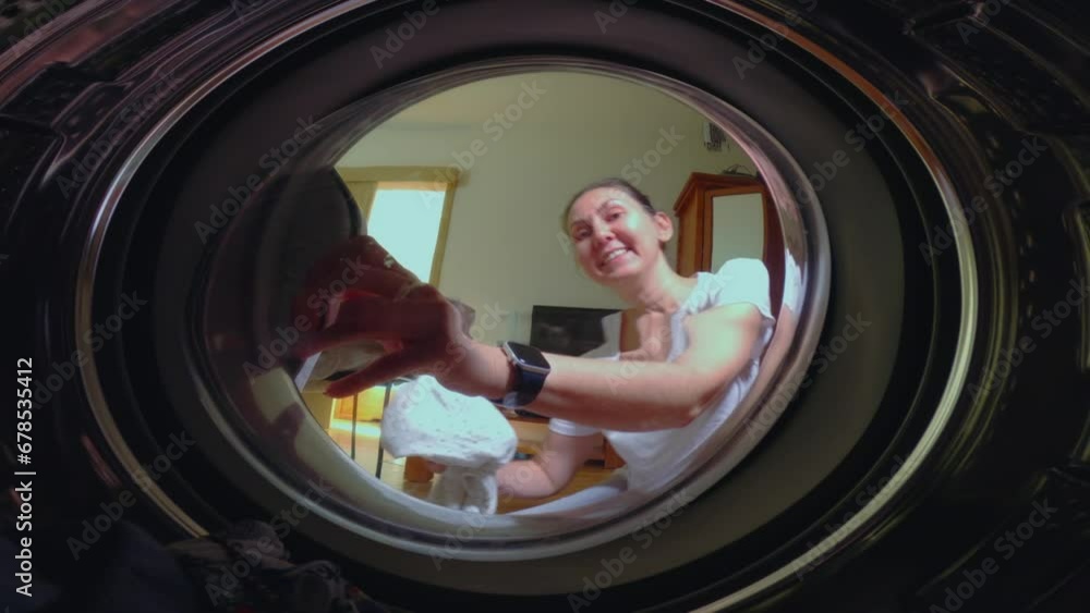 A woman with her little daughter puts laundry in the washing machine and prepares to wash the clothes. High quality 4k footage A woman with her little daughter puts laundry in the washing machine and prepares to wash the clothes. High quality 4k footage