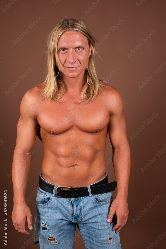 Young attractive man with an athletic body posing on a brown background.