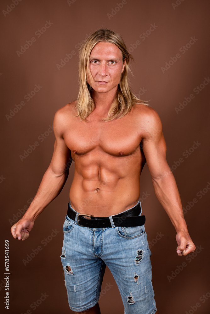 Young attractive man with an athletic body posing on a brown background. Young attractive man with an athletic body posing on a brown background.