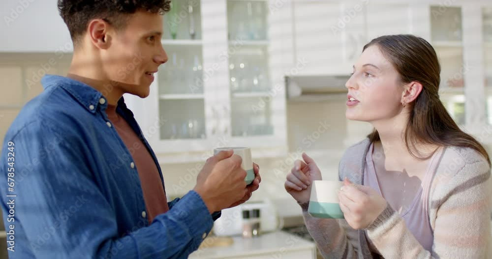Happy diverse couple talking and drinking coffee in kitchen at home, in slow motion Happy diverse couple talking and drinking coffee in kitchen at home, in slow motion