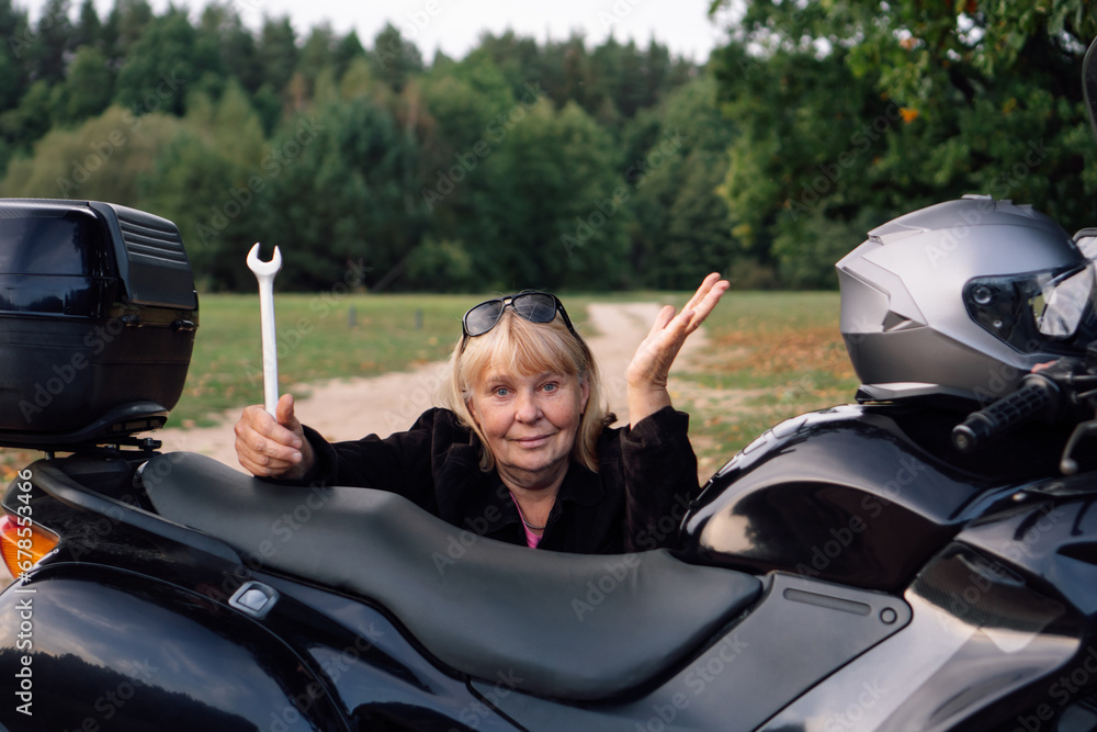 No problem, female mechanic with wrench gestures near black motorcycle on rural road on autumn day. No problem, female mechanic with wrench gestures near black motorcycle on rural road on autumn day.