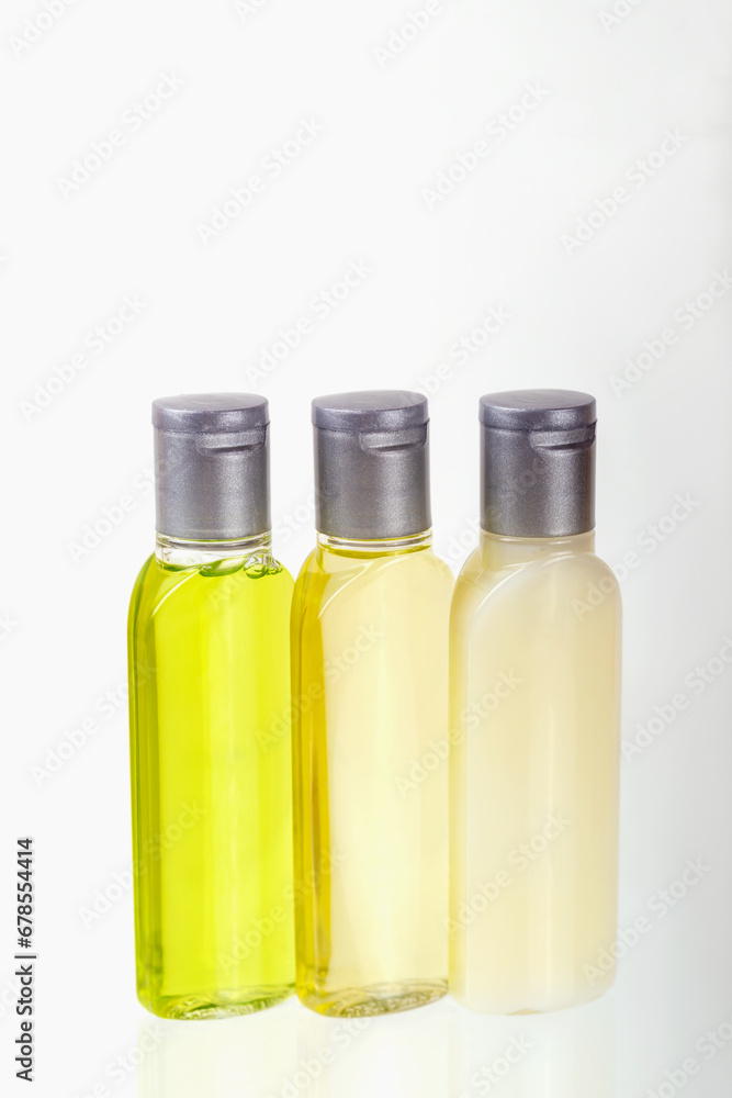Travel cosmetic set of three small bottles of cosmetics on white background. Shampoo, shower gel, body lotion. Travel, trips, hotels. Cosmetics mockup, advertising. Vertically