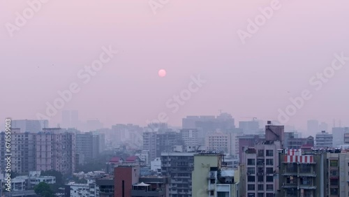 Aerial view of Mumbai city with air pollution while revealing cityscape, buildings as birds cross the frame. Pedestal down reveal of Indian city with poor AQI