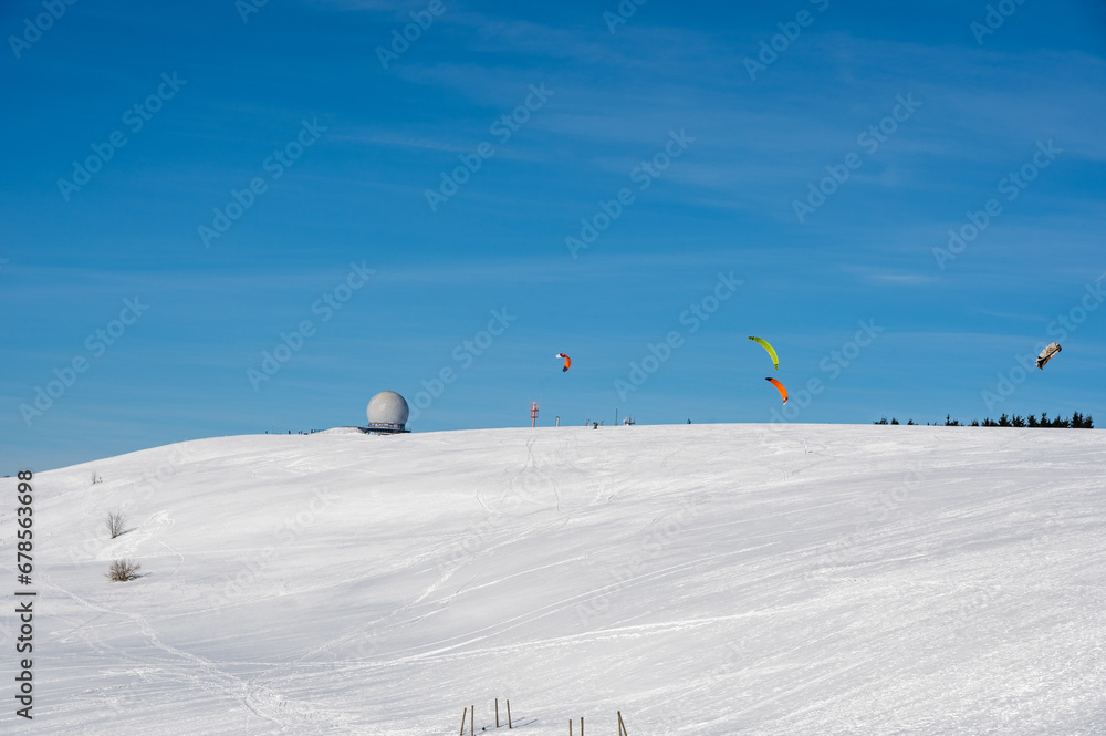 Kite surfing on the Wasserkuppe with Radome in the snow with a blue sky Kite surfing on the Wasserkuppe with Radome in the snow with a blue sky