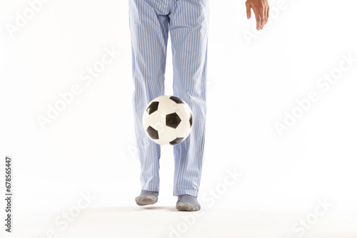 Fototapeta Naklejka Na Ścianę i Meble -  Young man in pajama playing football. Legs. Night wear