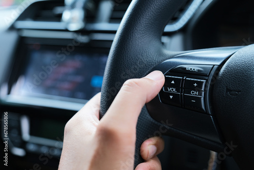 A car driver hand adjusting the sound volume using button on streering wheels photo