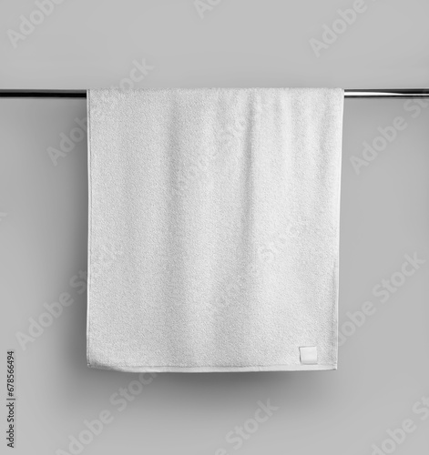 Mockup of a terry white towel with a label on a metal bar, hanging towelling for design, branding. photo