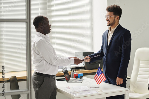 Happy African American man getting approved visa from specialist of visa center