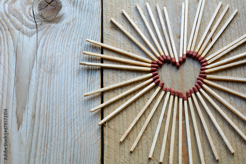 Childish heart from matches on the wooden background. Many long matches in heart form for men