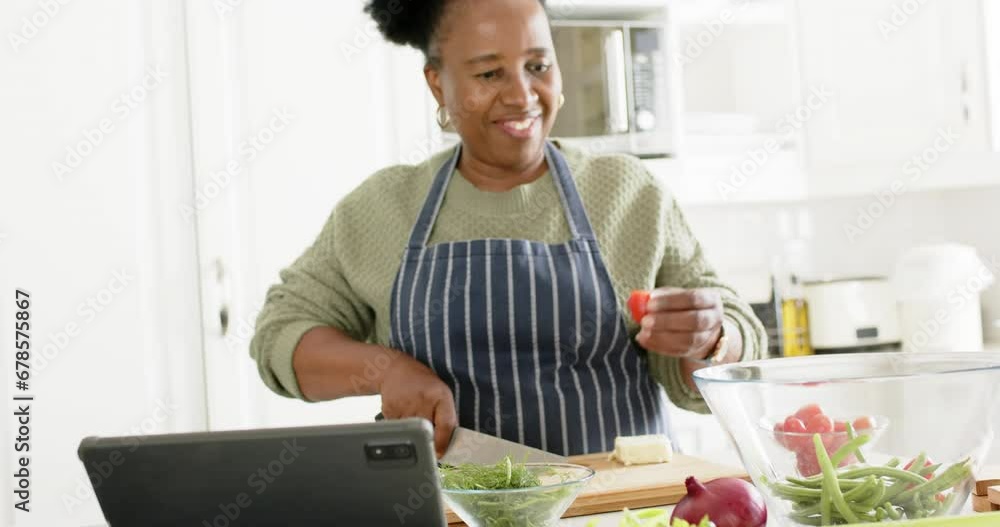 Happy african american senior woman chopping vegetables and dancing in sunny kitchen, slow motion Happy african american senior woman chopping vegetables and dancing in sunny kitchen, slow motion