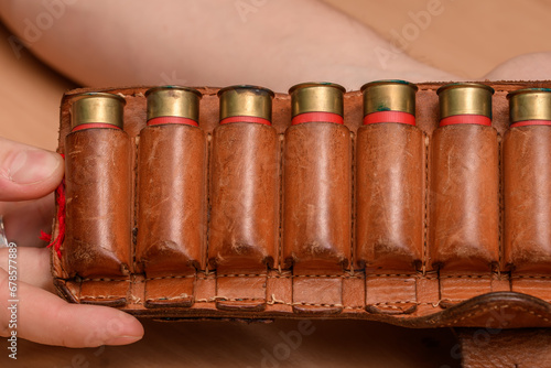 Obraz na plátně Skórzane etui na naboje do broni myśliwskiej trzymane w dlomiach
