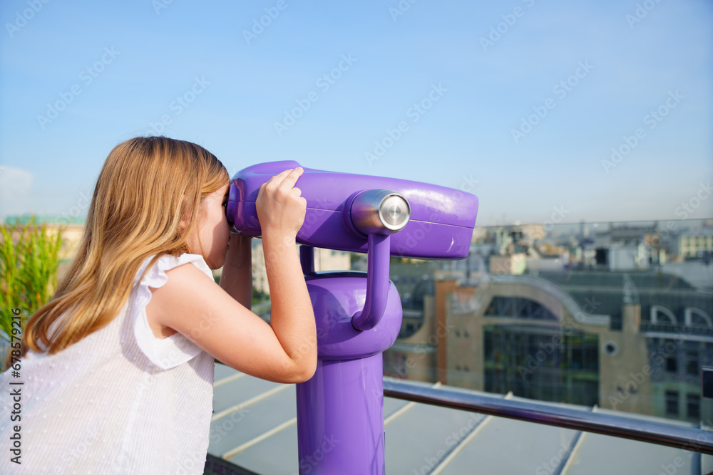 a teenage girl looks into the Binoscope from the observation deck at a height. 
