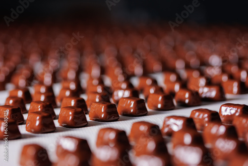 Sweets candy with chocolate on conveyor line factory. Process cocoa glazing.