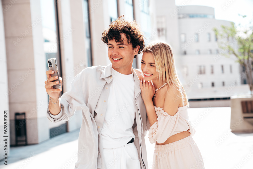 Young smiling beautiful woman and her handsome boyfriend in casual summer clothes. Happy cheerful family. Female having fun. Couple posing in street. Hold smartphone, use phone apps, look at screen Young smiling beautiful woman and her handsome boyfriend in casual summer clothes. Happy cheerful family. Female having fun. Couple posing in street. Hold smartphone, use phone apps, look at screen