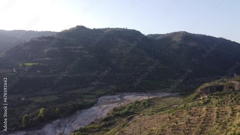 Flying Above Winding River Between Hills With Sun Creating Shadows Flying Above Winding River Between Hills With Sun Creating Shadows