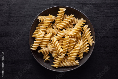 Uncooked fusilli pasta. Uncooked italian pasta on plate. Top view.