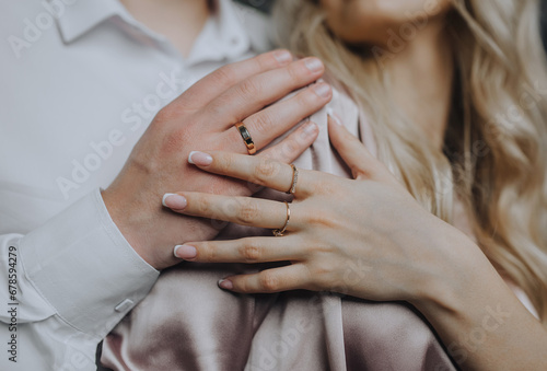 Hands with gold rings on the fingers of an embracing man and woman, bride and groom at a wedding. Photography, close-up portrait.
